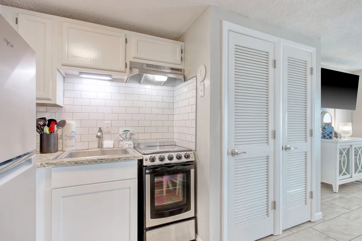 A closer look at the kitchen area, focusing on a sleek stainless steel stove, under-cabinet lighting, granite countertops, and clean white cabinetry. The environment is spotless and contemporary, highlighting cooking essentials and an ambiance that encourages meal preparation and experimentation.