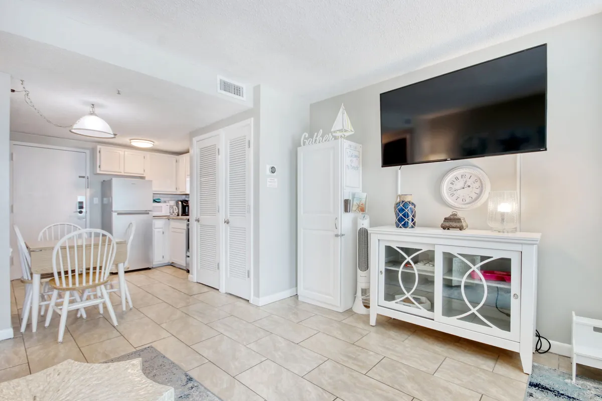 This image captures a cozy open-plan space featuring a dining area, living area with a sofa, a television, and decorative items. The arrangement of furniture highlights the seamless connection between the living and dining zones, and soft lighting contributes to an inviting ambiance.